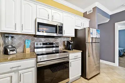 a kitchen with white cabinets and a stainless steel refrigerator at Ocean Reef Beach Resort! Beach Front! Free Seasonal Beach Chairs! by Dolce Vita Getaways PCB in Panama City Beach