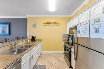 a kitchen with a sink and a refrigerator at Ocean Reef Beach Resort! Beach Front! Free Seasonal Beach Chairs! by Dolce Vita Getaways PCB in Panama City Beach