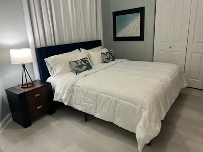 a bedroom with a large bed and a night stand with a lamp at Shores of Panama Condo With Same Level Parking in Panama City Beach