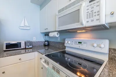 a kitchen with a stove and a microwave at Shores of Panama Condo With Same Level Parking in Panama City Beach