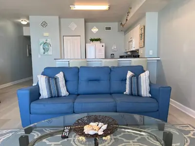 a blue couch in a living room with a table at Shores of Panama Condo With Same Level Parking in Panama City Beach