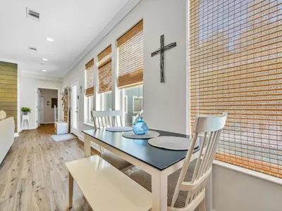 a dining room with a table and a cross on the wall at Aweigh From Home in Santa Rosa Beach