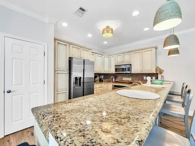 a kitchen with a granite counter top and a refrigerator at Aweigh From Home in Santa Rosa Beach