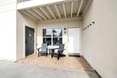 a patio with two chairs and a table on a house at Palm Grove at Sago Sands Unit A in Seagrove Beach