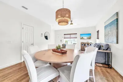a dining room with a wooden table and white chairs at Palm Grove at Sago Sands Unit A in Seagrove Beach