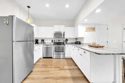 a white kitchen with white cabinets and a refrigerator at Palm Grove at Sago Sands Unit A in Seagrove Beach