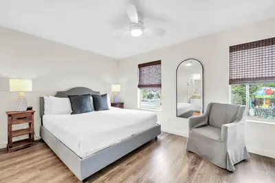 a bedroom with a bed and a chair and a mirror at Palm Grove at Sago Sands Unit A in Seagrove Beach