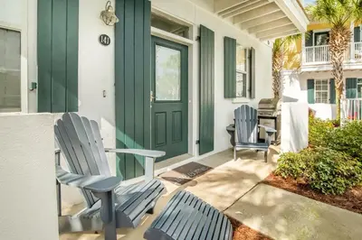 a porch with two chairs and a green door at Coastal Blue 141 in Seagrove Beach