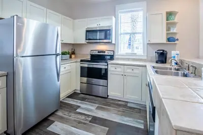 a kitchen with white cabinets and a stainless steel refrigerator at Coastal Blue 141 in Seagrove Beach
