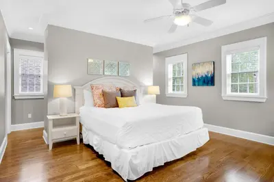 a bedroom with a white bed and two windows at Captain's Cottage in Watersound Beach