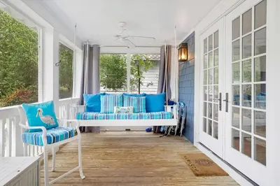 a porch with blue and white furniture and windows at Captain's Cottage in Watersound Beach