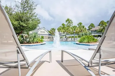 a fountain in the middle of a swimming pool with two chairs at Captain's Cottage in Watersound Beach