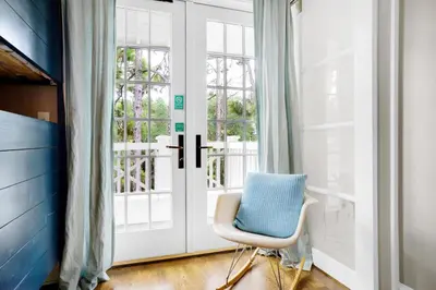a white door with a chair next to a window at Captain's Cottage in Watersound Beach
