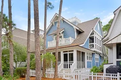 a blue house with a white fence and palm trees at Captain's Cottage in Watersound Beach