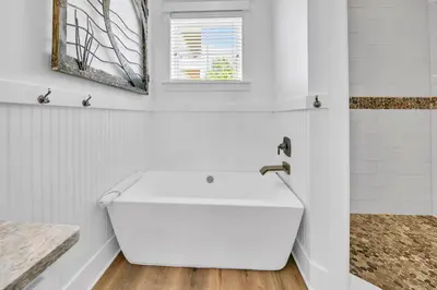 a white bathroom with a sink and a window at Kiwi Grove in Seagrove Beach