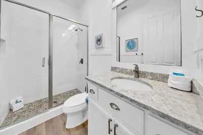 a white bathroom with a toilet and a sink at Kiwi Grove in Seagrove Beach