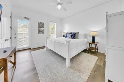 a white bedroom with a bed and a table at Kiwi Grove in Seagrove Beach