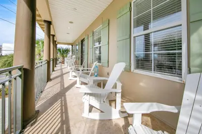 a balcony with white chairs and windows on a building at Kiwi Grove in Seagrove Beach