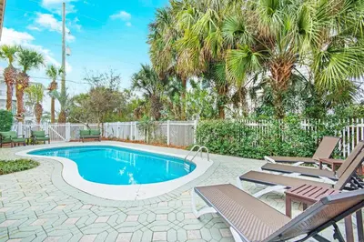 a swimming pool in a yard with chairs and trees at Kiwi Grove in Seagrove Beach
