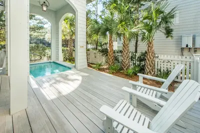 a porch with two white chairs and a swimming pool at The Nautilus in Watersound Beach