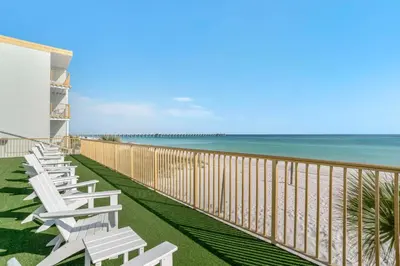 a row of white chairs on the beach at Chateau Beachfront Hotel, a By the Sea Resort in Panama City Beach