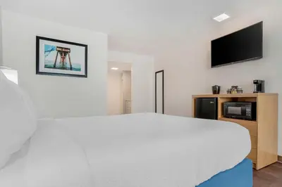 a bedroom with a white bed and a flat screen tv at Chateau Beachfront Hotel, a By the Sea Resort in Panama City Beach