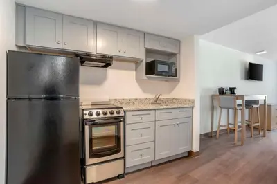 a kitchen with a stainless steel refrigerator and a table at Chateau Beachfront Hotel, a By the Sea Resort in Panama City Beach