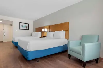 a bed and a chair in a hotel room at Chateau Beachfront Hotel, a By the Sea Resort in Panama City Beach