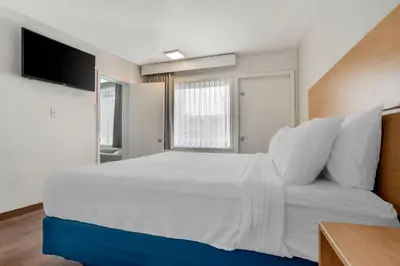 a bedroom with a large white bed and a television at Chateau Beachfront Hotel, a By the Sea Resort in Panama City Beach