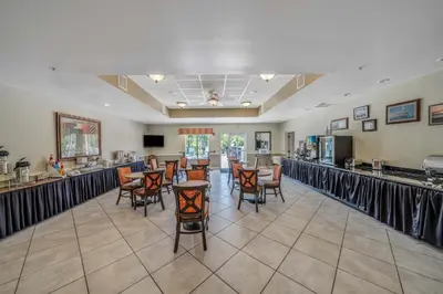 a large room with a bar with chairs and tables at La Quinta by Wyndham PCB Coastal Palms in Panama City Beach