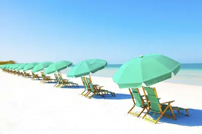 a row of beach chairs with umbrellas on the beach at Sun and Sand in Inlet Beach