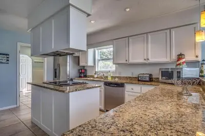 a kitchen with white cabinets and granite counter tops at Sun and Sand in Inlet Beach
