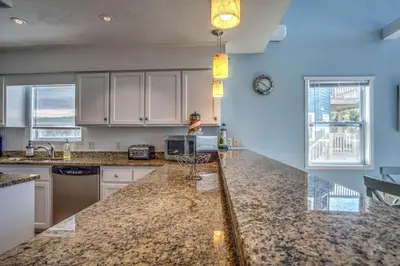 a kitchen with marble counter tops and white cabinets at Sun and Sand in Inlet Beach