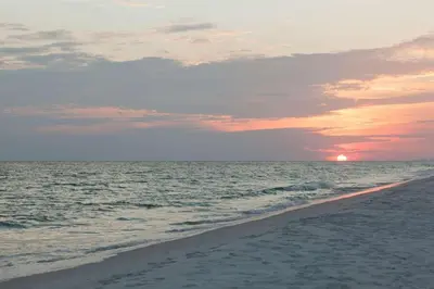 a sunset on a beach with the ocean at Blue Sails in Inlet Beach