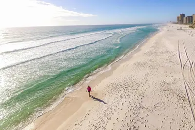a person walking on a beach near the ocean at SpringHill Suites by Marriott Panama City Beach Beachfront in Panama City Beach