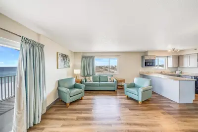 a living room with two chairs and a kitchen at Sugar Sands Beachfront Hotel, a By The Sea Resort in Panama City Beach
