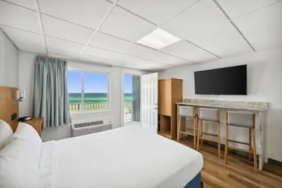 a hotel room with a bed and a flat screen tv at Sugar Sands Beachfront Hotel, a By The Sea Resort in Panama City Beach