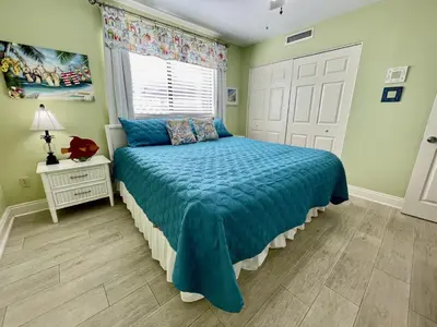 a bedroom with a bed with a blue comforter and a window at Summer House 101 A in Panama City Beach