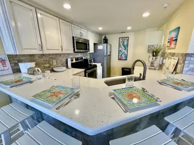 a kitchen with a large island with chairs in it at Summer House 101 A in Panama City Beach