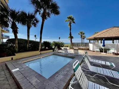 a swimming pool with two lounge chairs and palm trees at Summer House 101 A in Panama City Beach