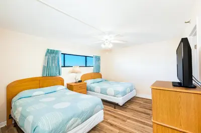 a bedroom with two beds and a flat screen tv at Landmark Holiday Beach in Panama City Beach