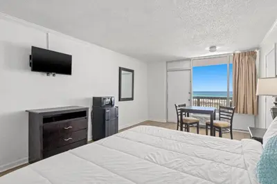 a hotel room with a bed and a table and chairs at The Reef At Seahaven Beach Resorts in Panama City Beach