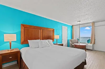 a bedroom with a large bed with a blue wall at The Reef At Seahaven Beach Resorts in Panama City Beach