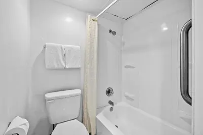a white bathroom with a toilet and a shower at The Reef At Seahaven Beach Resorts in Panama City Beach