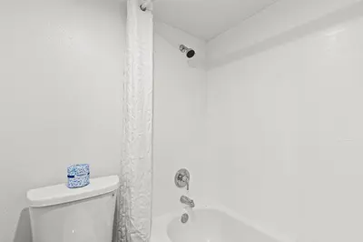 a white bathroom with a toilet and a shower at The Reef At Seahaven Beach Resorts in Panama City Beach