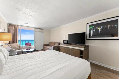 a hotel room with a bed and a flat screen tv at Seahaven Beach Hotel Panama City Beach in Panama City Beach