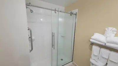 a bathroom with a glass shower with towels at Garner Hotel Panama City Beach Northeast by IHG in Panama City Beach