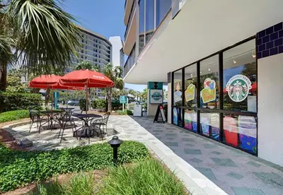 a table and chairs with an umbrella outside of a building at Windward 604 at Edgewater in Panama City Beach