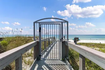 a gate at the beach with the ocean in the background at Walton Dunes 2 in Santa Rosa Beach
