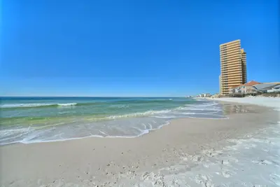 a beach with a tall building and the ocean at Aqua View Motel in Panama City Beach